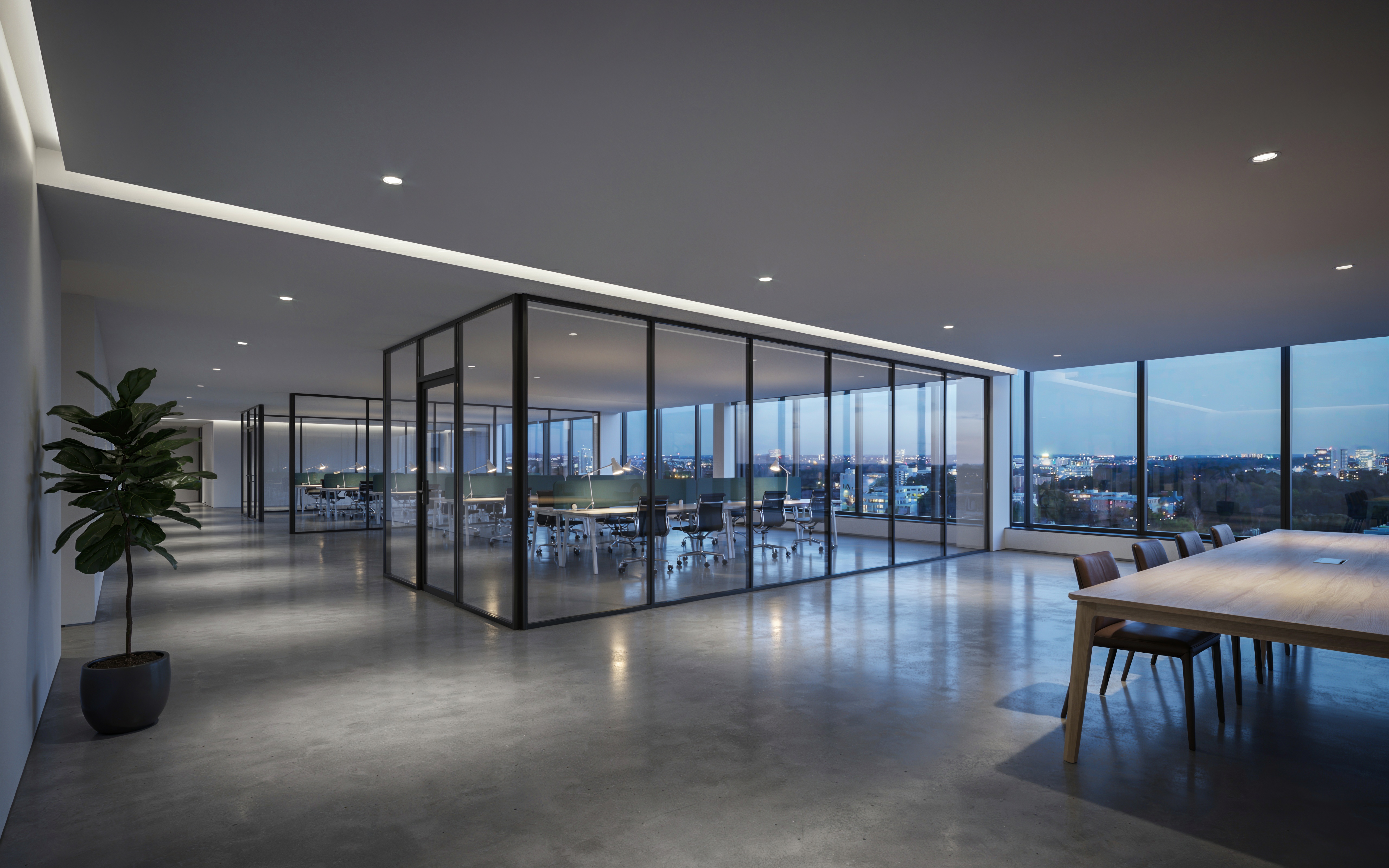 A spacious modern office floor at dusk with a glass meeting room and city view